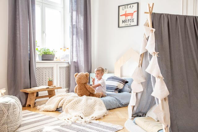 Kind mit Kuscheltier auf Montessori Bett